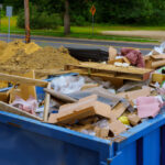 Blue,Construction,Debris,Container,Filled,With,Rock,And,Concrete,Rubble.