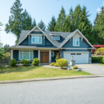 Luxury,Blue,House,With,Beautiful,Landscaping,On,A,Sunny,Day.