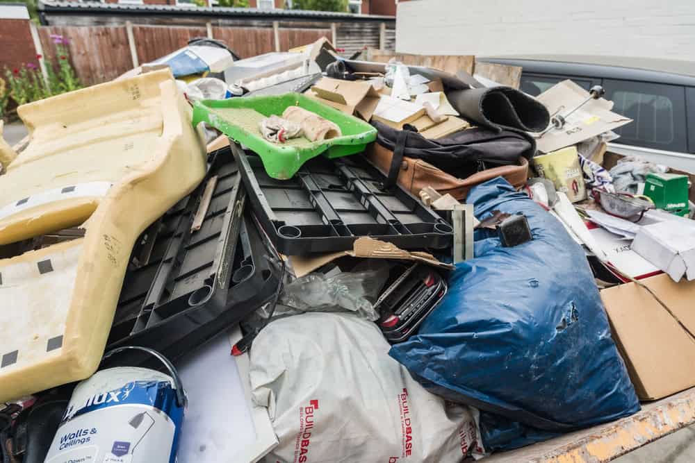 A pickup truck bed overloaded with plastic crates, cardboard boxes, bags, and mixed debris weaves through CA streets. This cluttered collection suggests a need for efficient junk removal in San Francisco County.