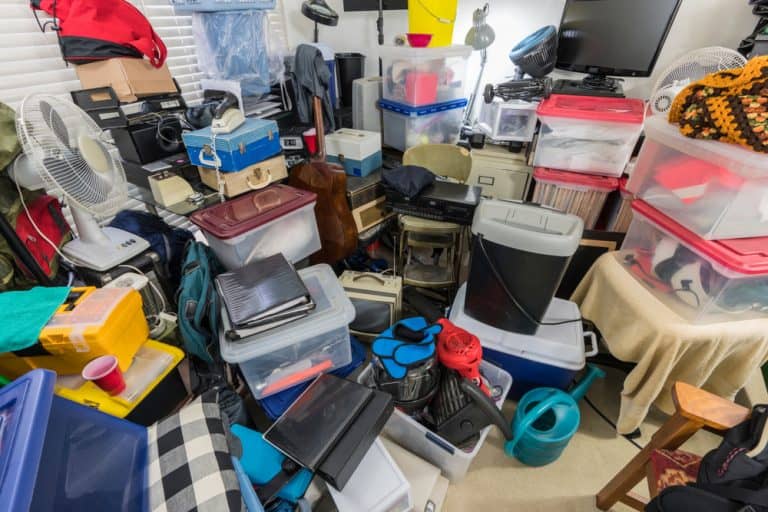 A cluttered room in CA filled with large plastic storage bins, boxes, fans, electronics, and bags stacked haphazardly&mdash;perfect for a Junk Removal San Francisco County service to help reclaim your space.